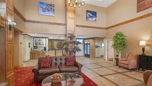 Eine großzügige Lobby mit einer braunen Ledersofa, einem Glastisch und einem roten Teppich mit Muster.