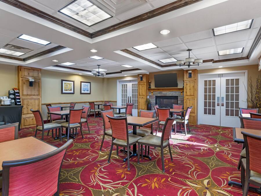 A hotel dining area with tables and chairs, a fireplace, and a television.