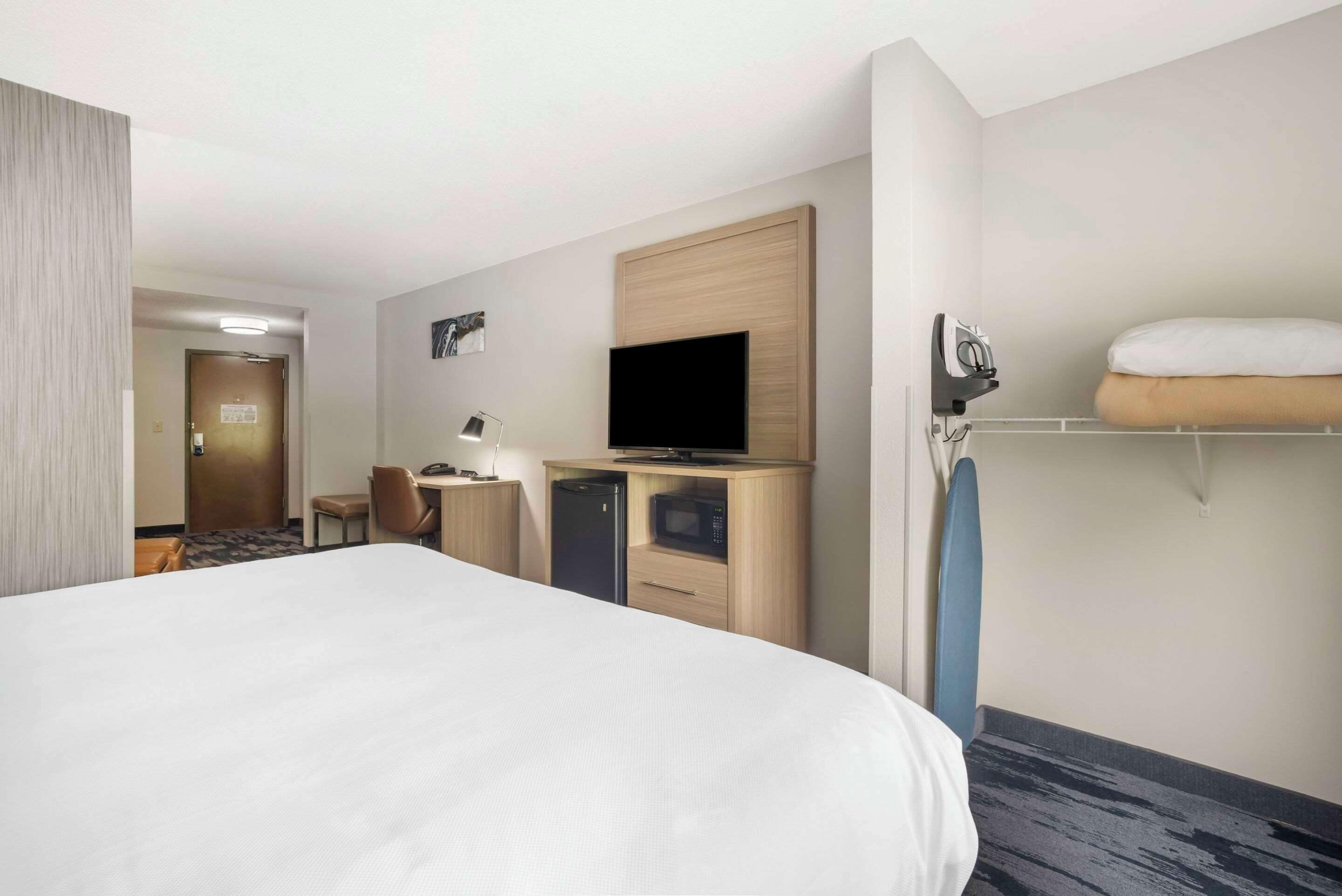 Une chambre d’hôtel avec un grand lit, un bureau avec un ordinateur, un four à micro-ondes et une télévision.