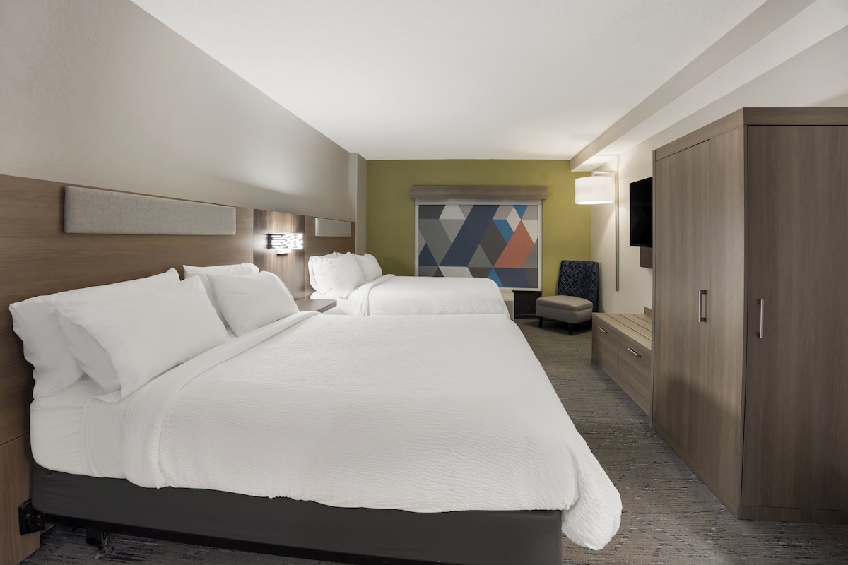 Une chambre d’hôtel avec un grand lit, un bureau, une chaise, une armoire et un téléviseur.