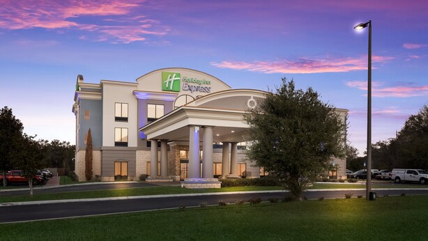 A Holiday Inn Express hotel with a modern design, featuring a large entrance, a fountain, and a well-maintained lawn. - Holiday Inn Express Hotel & Suites PERRY by IHG (Perry)