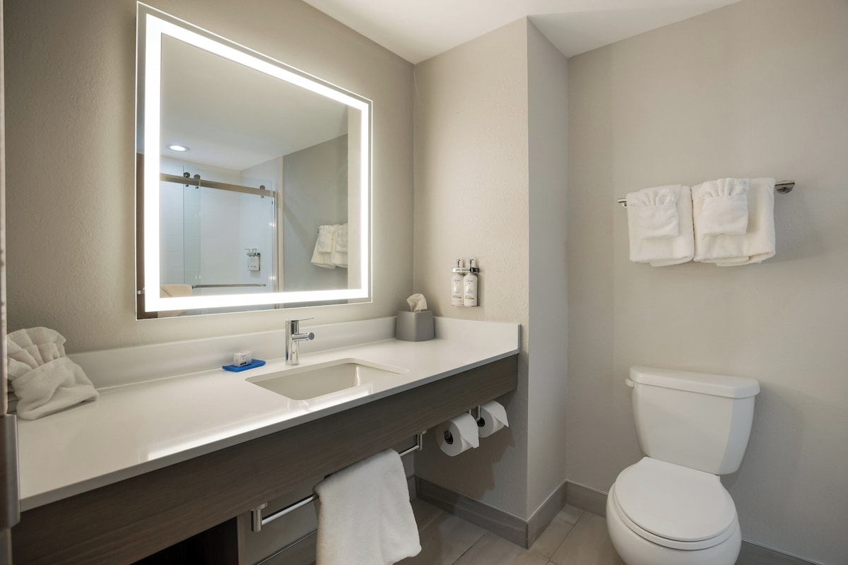 Une salle de bain moderne avec un grand miroir, un lavabo, des toilettes et un porte-serviettes.