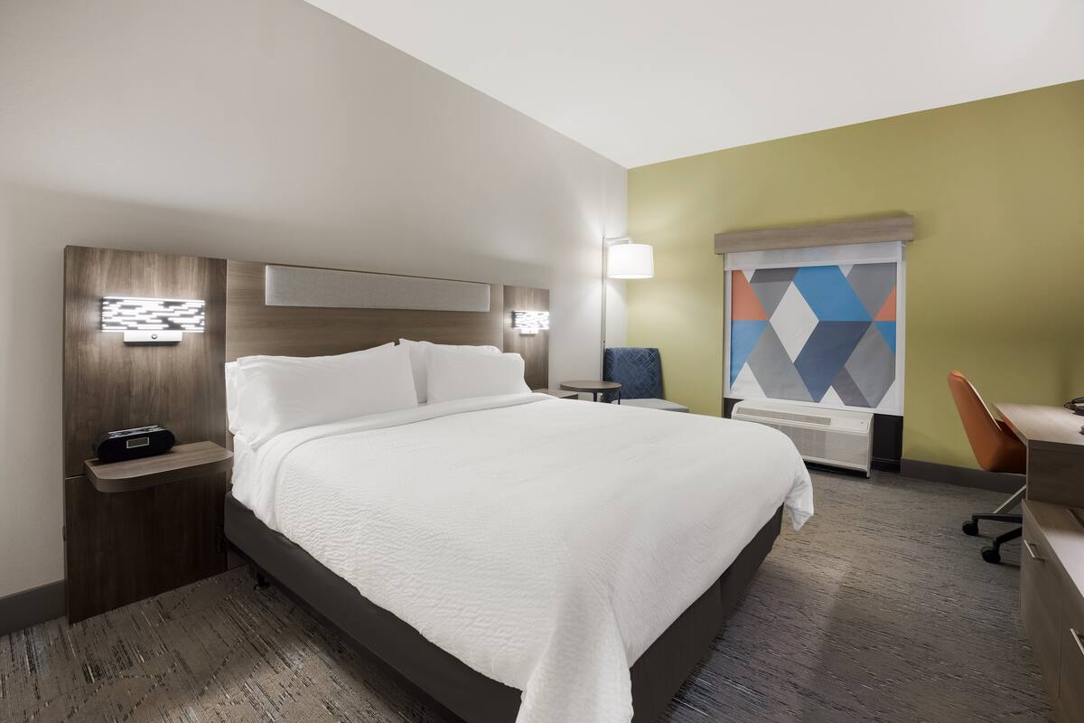 A hotel room with a large bed, bedside tables, a desk, and a chair.