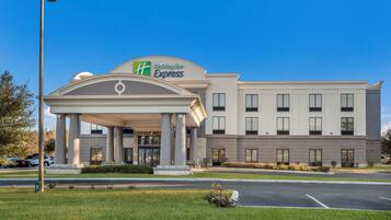 Edificio de Holiday Inn Express con entrada cubierta, columnas y estacionamiento.
