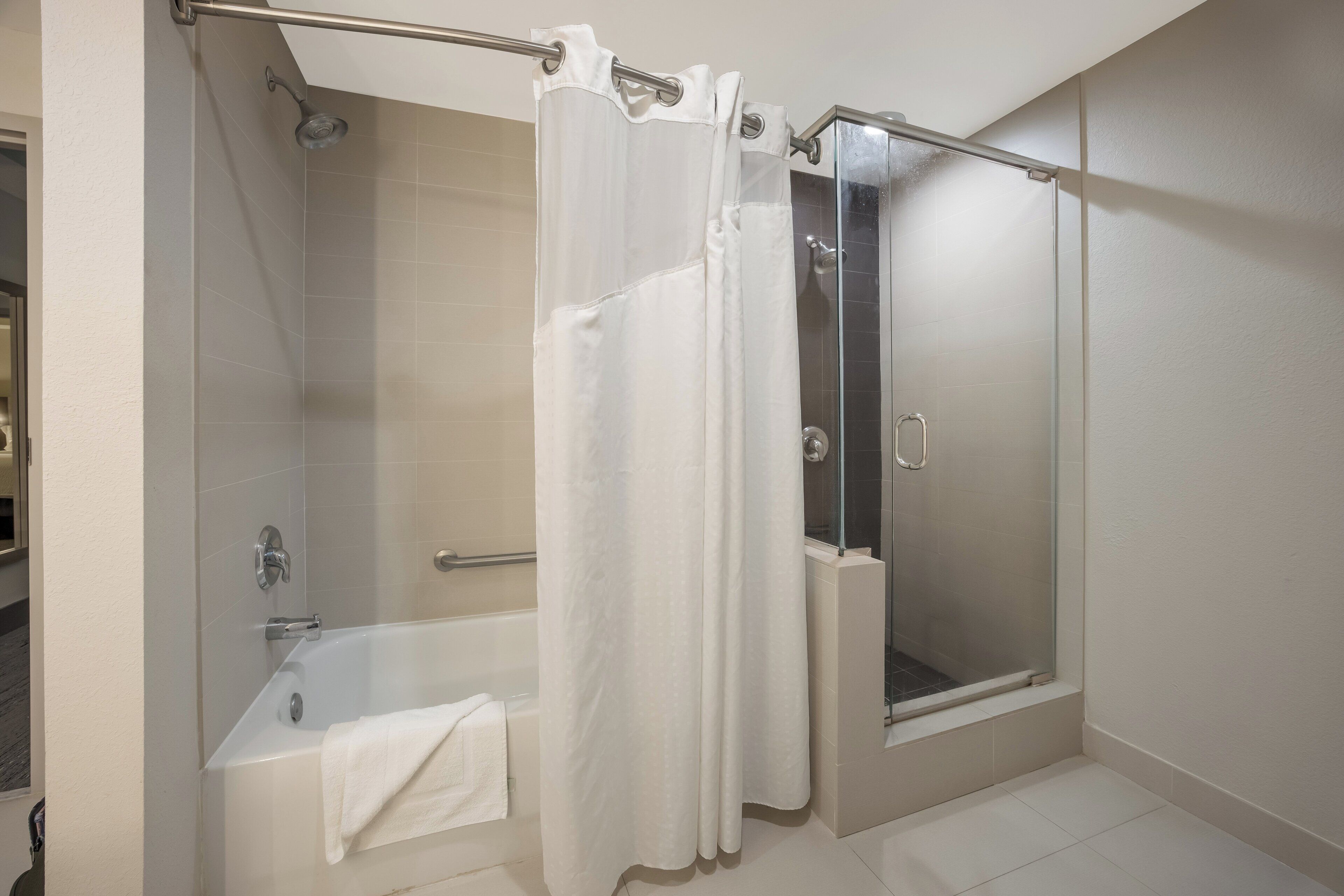 A bathroom with a bathtub, a shower, and a glass-enclosed shower stall.