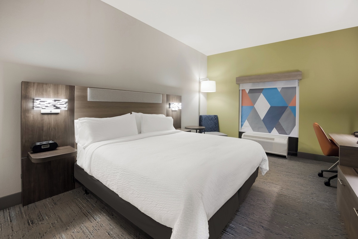 Une chambre d’hôtel avec un grand lit, des tables de chevet, un bureau et une chaise.