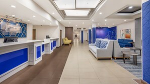A modern hotel lobby with a reception desk, seating area, and a hallway leading to other rooms. - Holiday Inn Express Hotel & Suites PERRY by IHG (Perry)