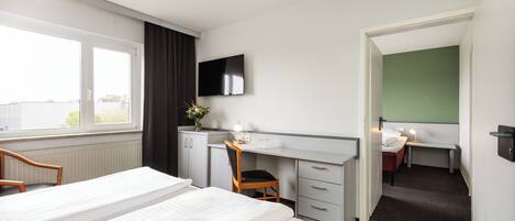 A hotel room with a bed, a desk, a chair, a TV, and a bathroom.