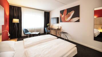 A hotel room with two beds, a desk, a chair, a TV, and a painting on the wall.