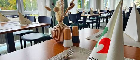 A dining area with tables set for a meal, featuring a menu and cutlery.