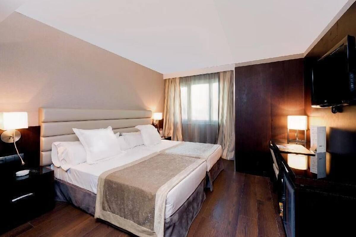 Une chambre d’hôtel avec un grand lit, des lampes de chevet, une télévision et un plancher en bois.
