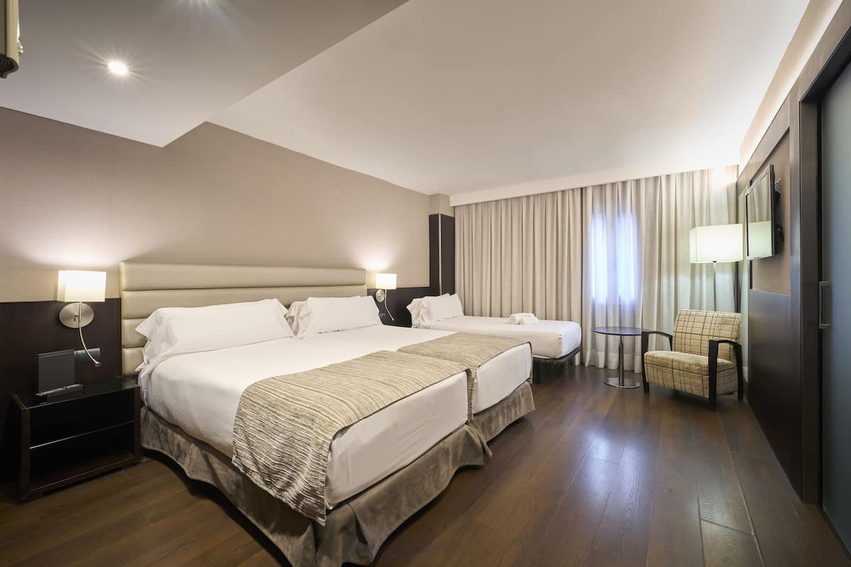 Une chambre d’hôtel avec deux lits, un bureau, une chaise et un téléviseur.