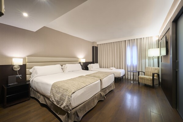 Une chambre d’hôtel avec deux lits, un bureau, une chaise et un téléviseur.