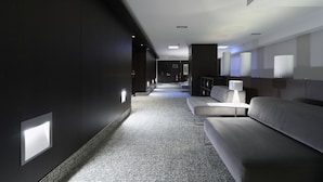Un vestíbulo moderno de hotel con un largo pasillo, una zona de estar y un mostrador de recepción.