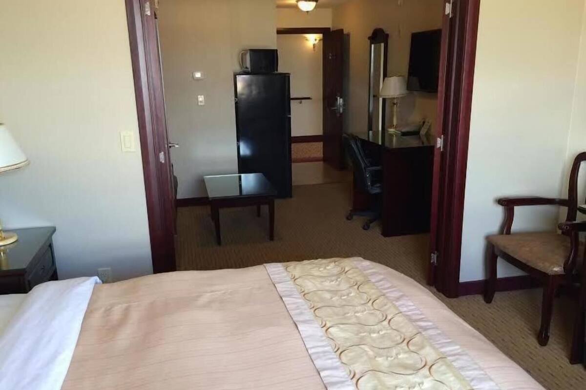 A hotel room with a bed, a desk, a chair, a wardrobe, and a television.