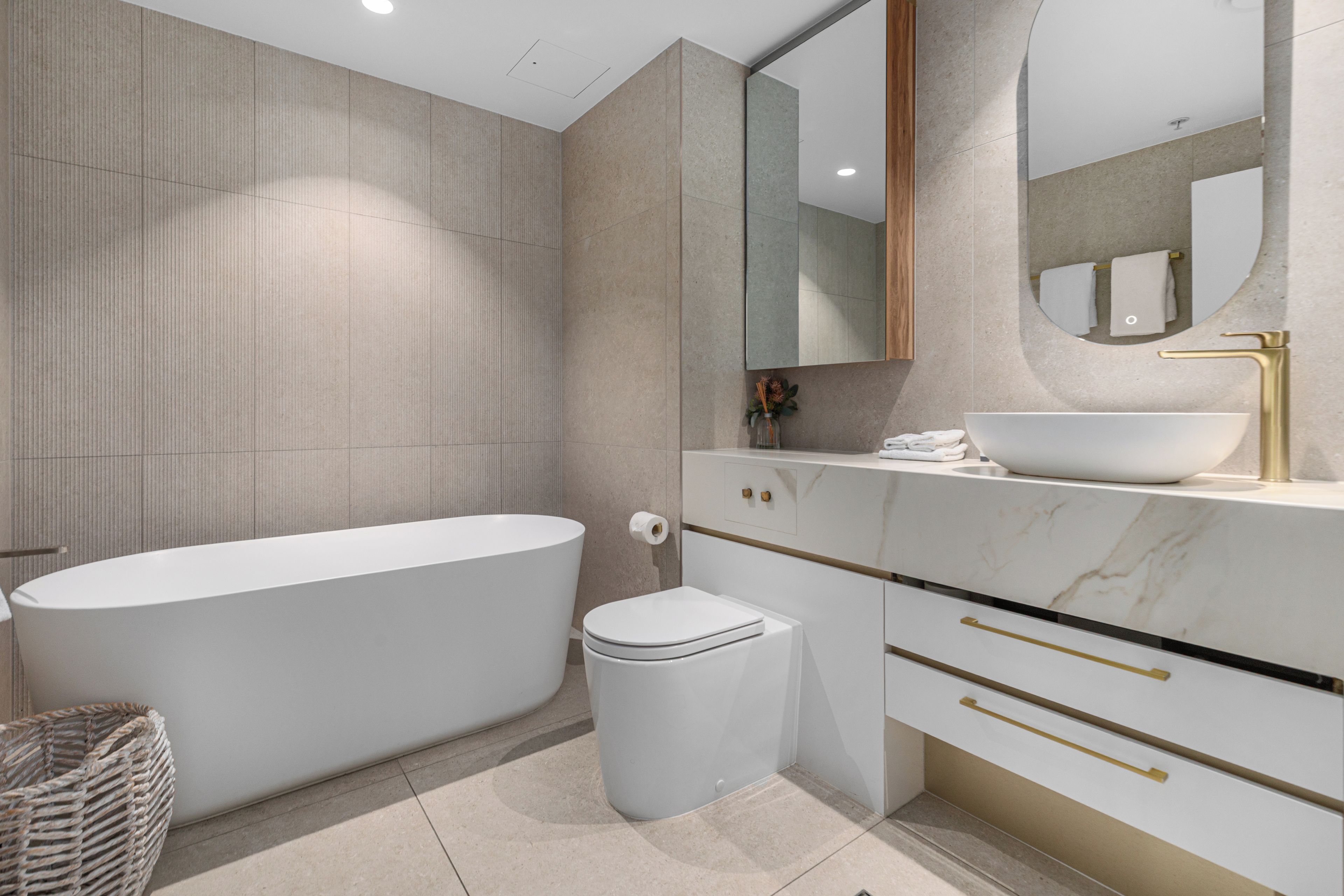 Un bagno moderno con una vasca freestanding, un water, un mobile lavabo con lavandino e uno specchio.