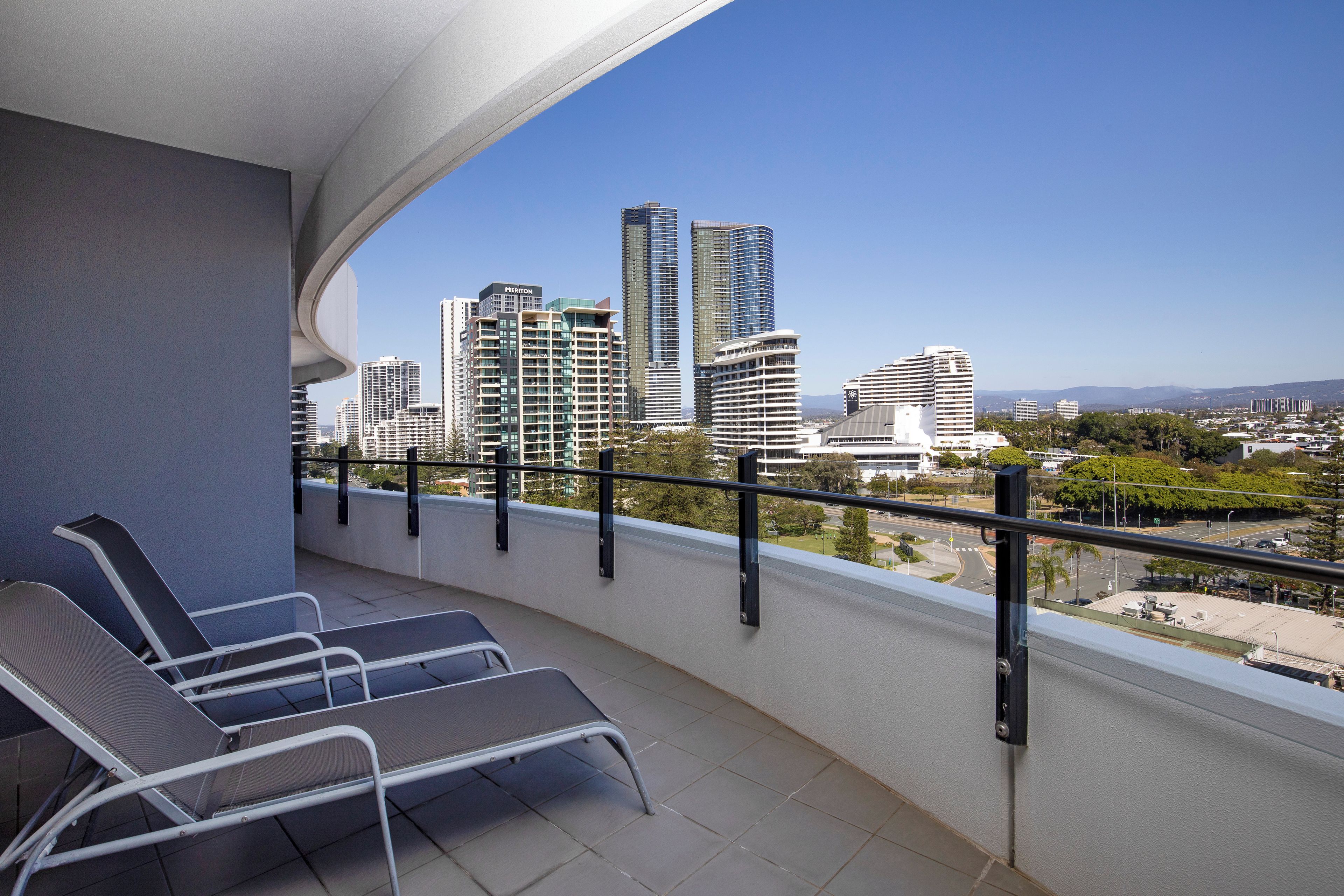 A balcony with a view of high-rise buildings, including a hotel named 'Meriton.'
