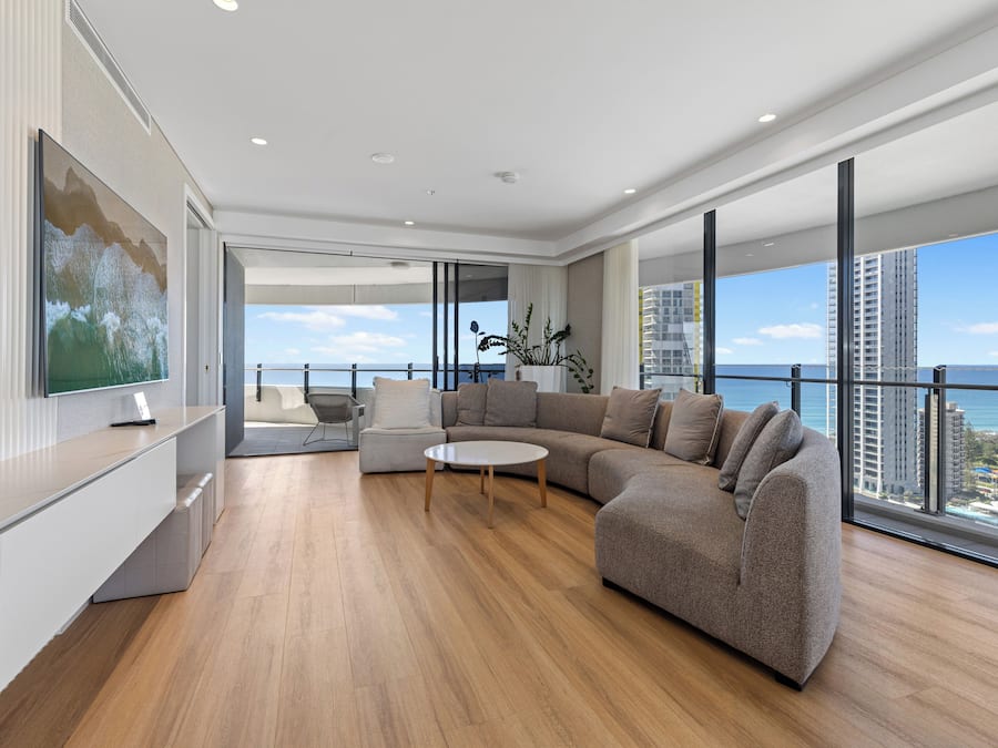 Uma sala de estar moderna com um sofá seccional grande, uma mesa de centro e uma televisão na parede.