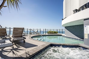 A pool area with lounge chairs and a hot tub, overlooking the ocean. - The Wave Resort (Broadbeach)