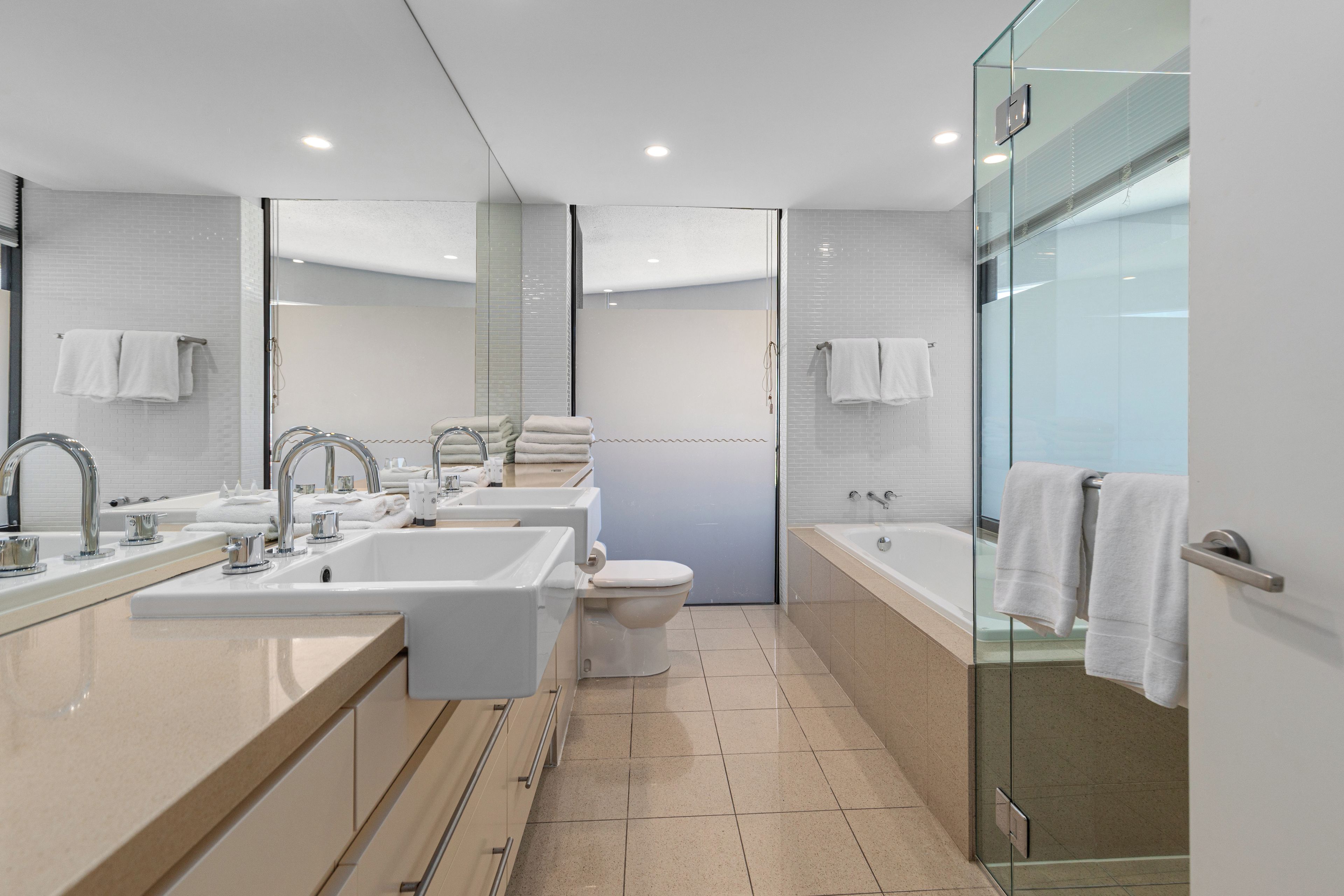 A modern bathroom with a glass shower enclosure, a bathtub, and a large mirror.