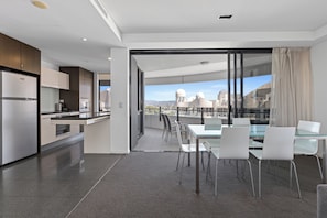 A modern kitchen with a dining area, large windows, and a view of a cityscape.