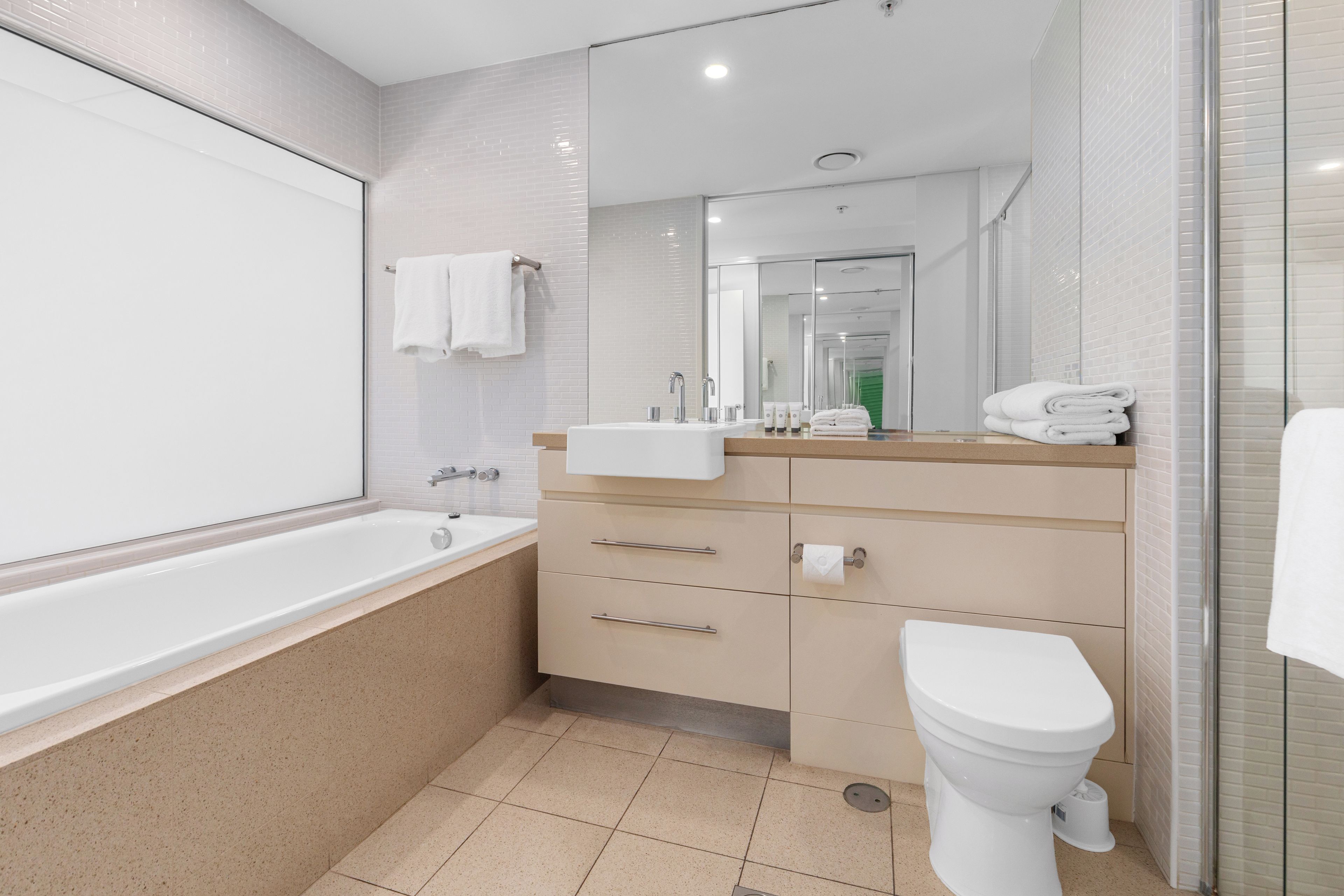 A modern bathroom with a bathtub, sink, vanity, and toilet.