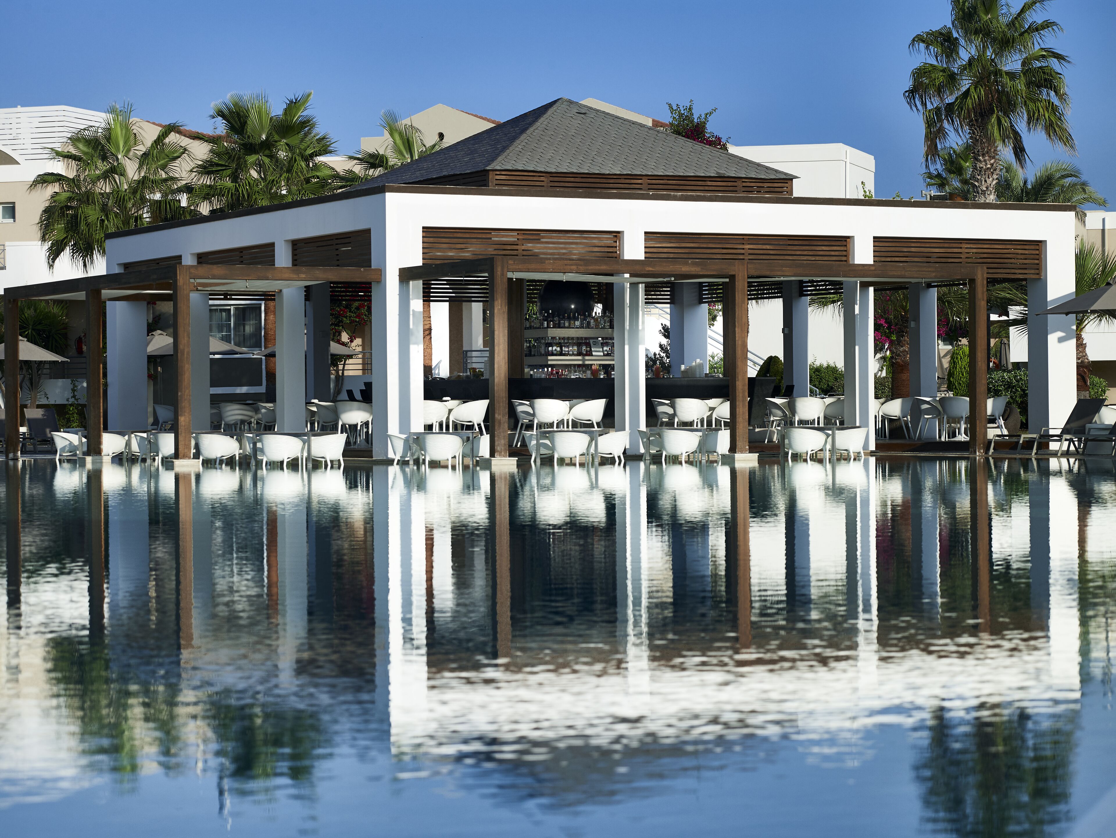 A poolside area with white lounge chairs and a bar.