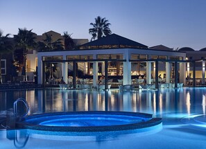 A modern hotel with a pool area, lounge chairs, and a covered seating area. - Pelagos Suites Hotel & Spa (Kos)