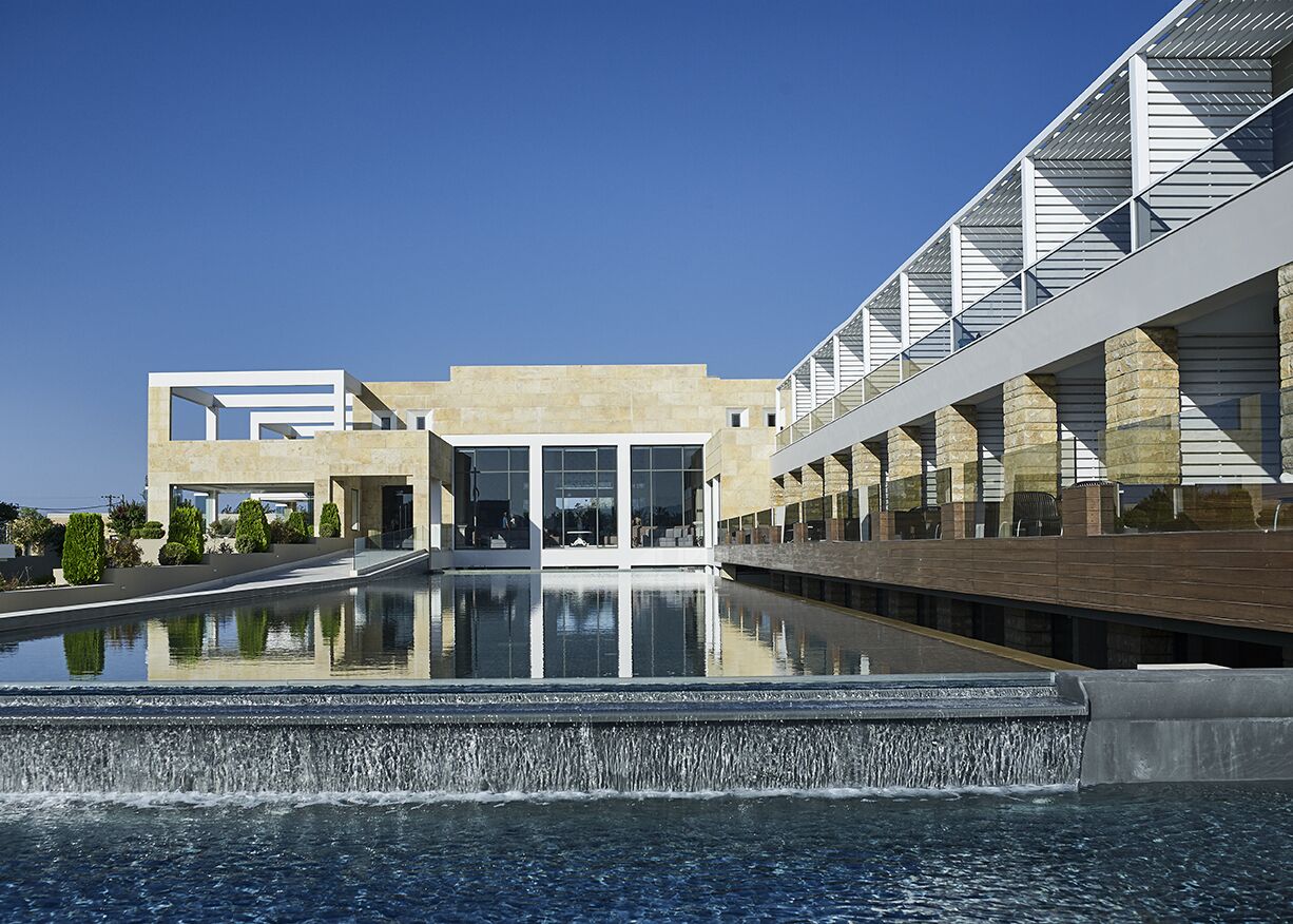 A modern building with a reflective pool and a bridge.