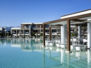 A pool area with clear water, lounge chairs, and umbrellas. - Pelagos Suites Hotel & Spa (Kos)