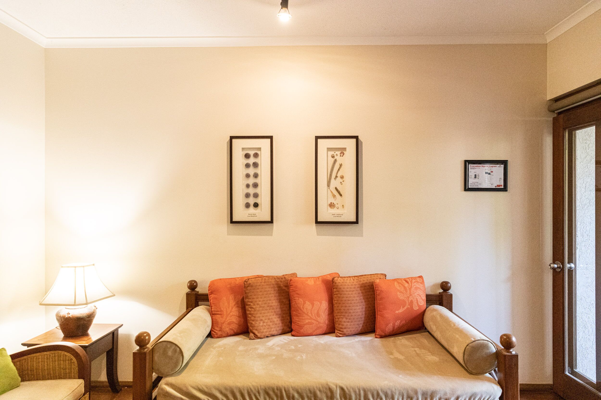 Un dormitorio con cama, mesita de noche con lámpara y cuadros en la pared.