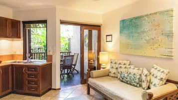 Relax in this open-plan living space with a kitchen, dining area, and balcony overlooking lush greenery.