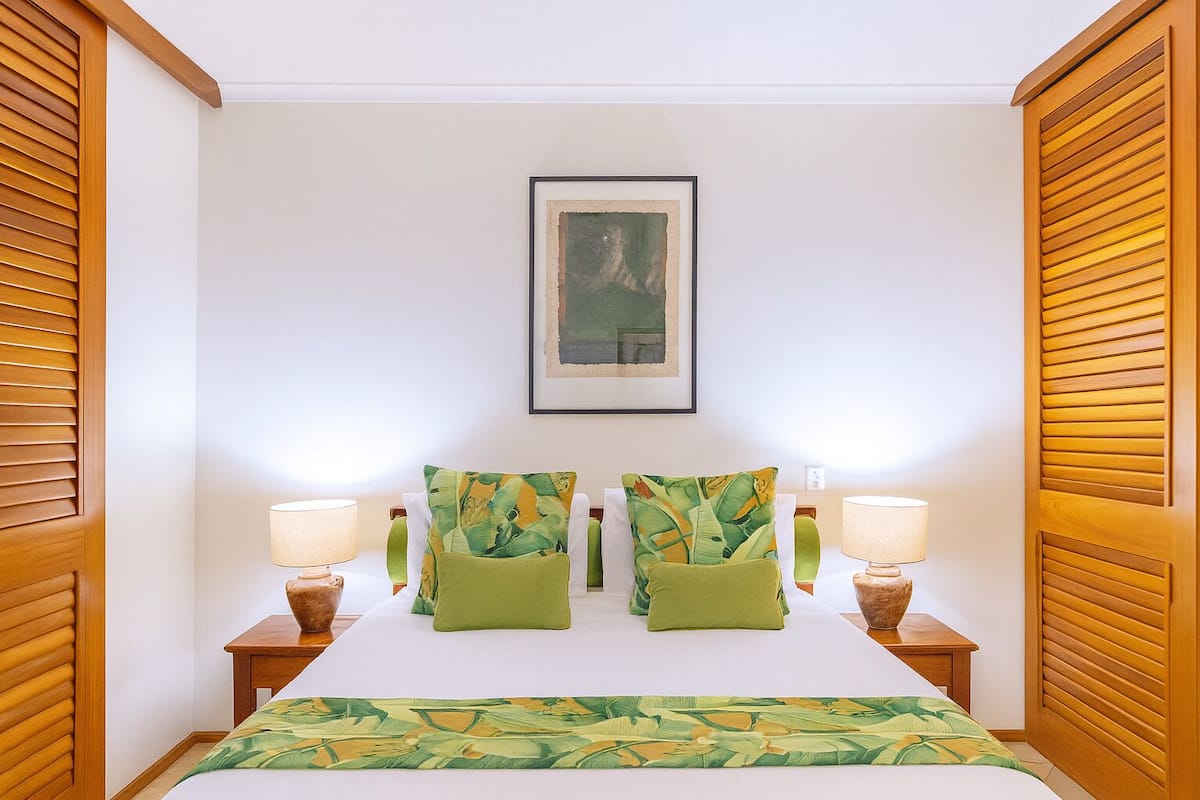 A hotel room with a bed, two nightstands, two lamps, and a framed picture on the wall.