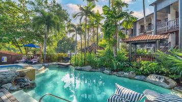 A pool area with lounge chairs and a wooden deck.
