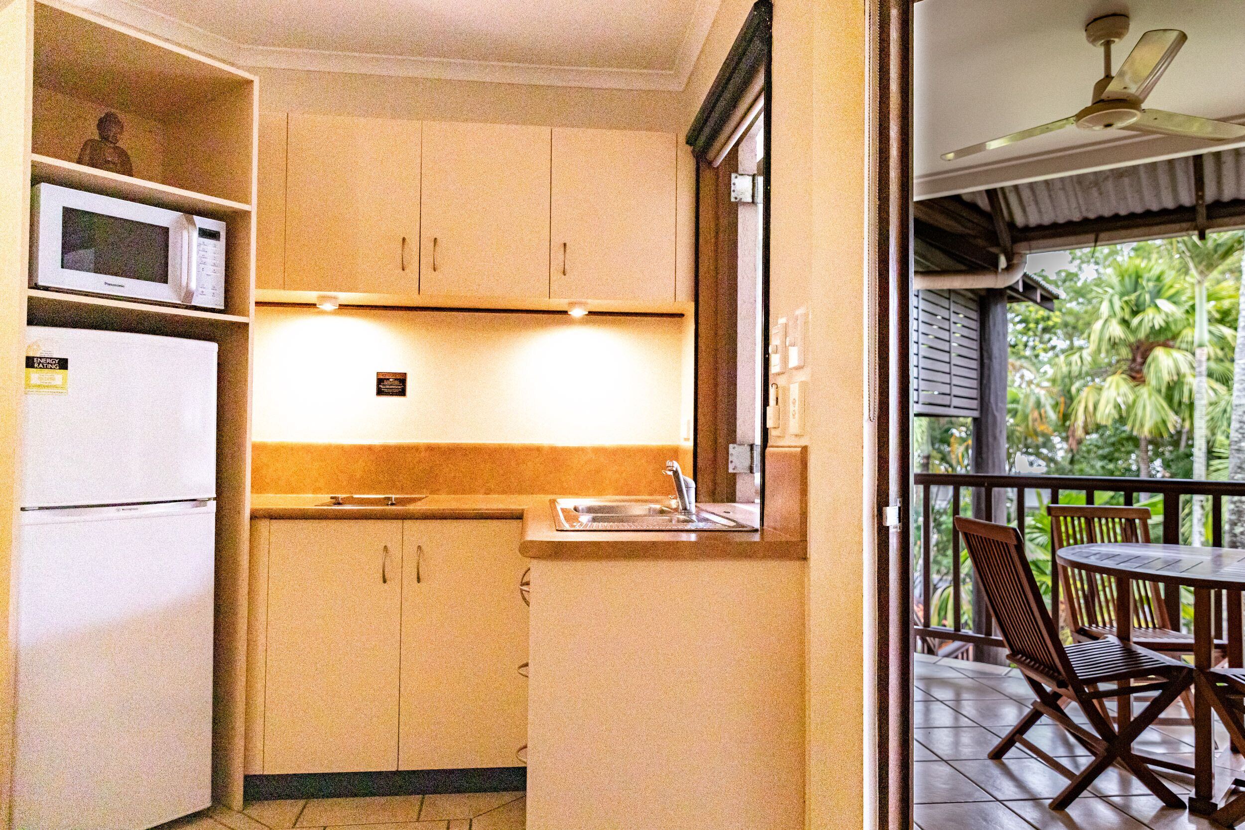Cocina compacta con microondas, refrigerador y pileta. Cuenta con un pequeño comedor con mesa y sillas.