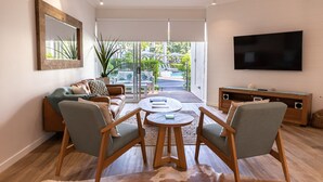 Una sala de estar moderna con un sofá, dos sillones, una mesa de centro y un televisor.