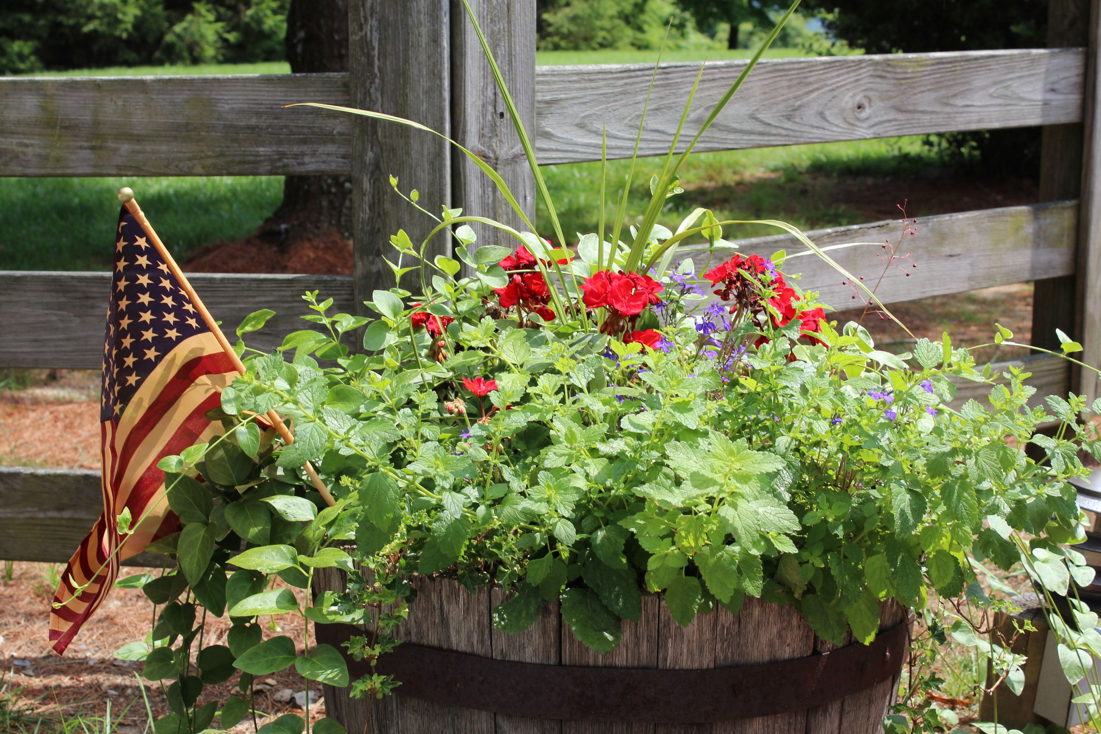 A wooden planter with a variety of flowers and an American flag.