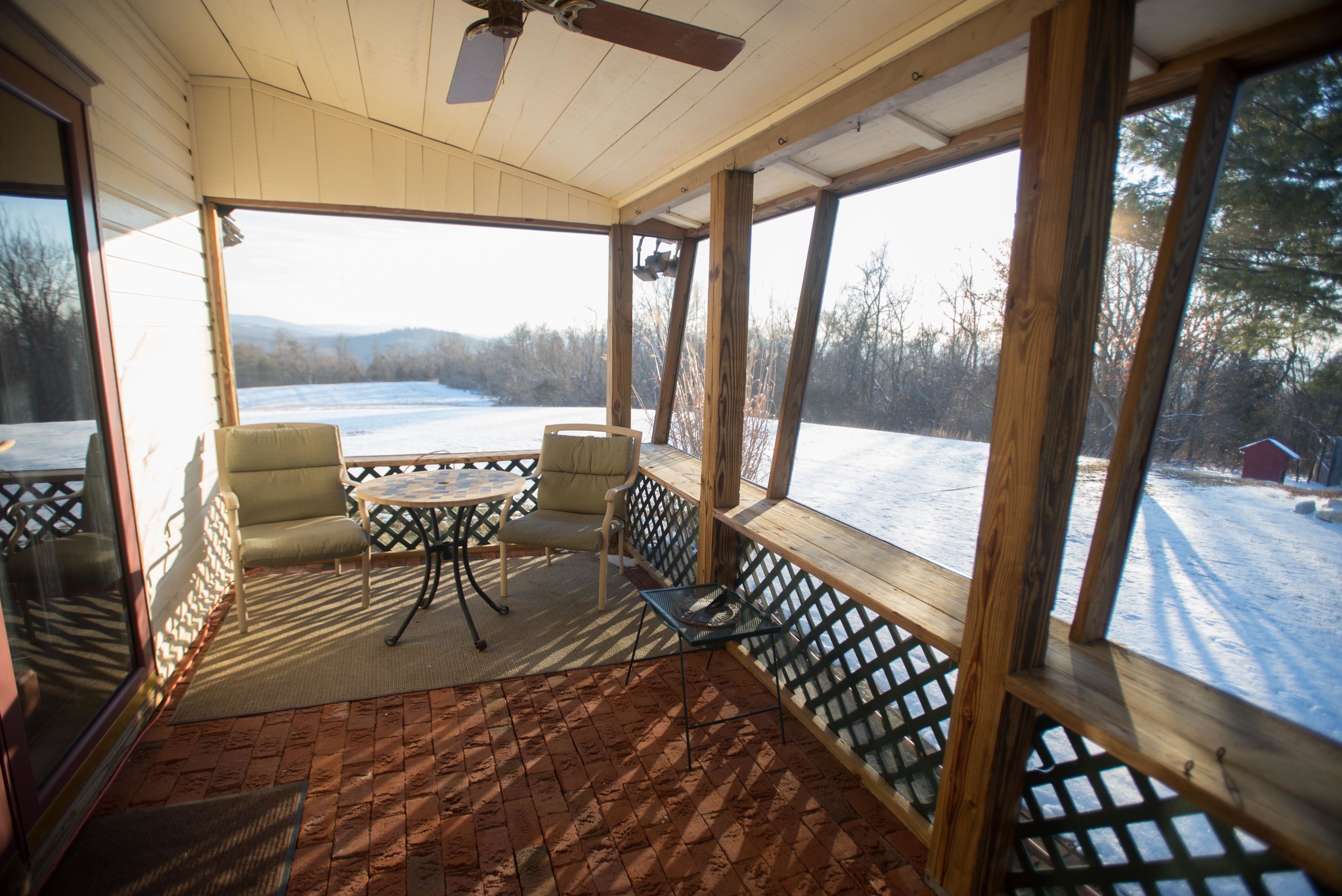 Un patio cubierto con vistas a un paisaje nevado, con una mesa y dos sillas.