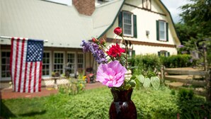 A house with a green roof and white walls, a flag, and a vase with flowers in the foreground. - Antietam Overlook Farm (Keedysville)