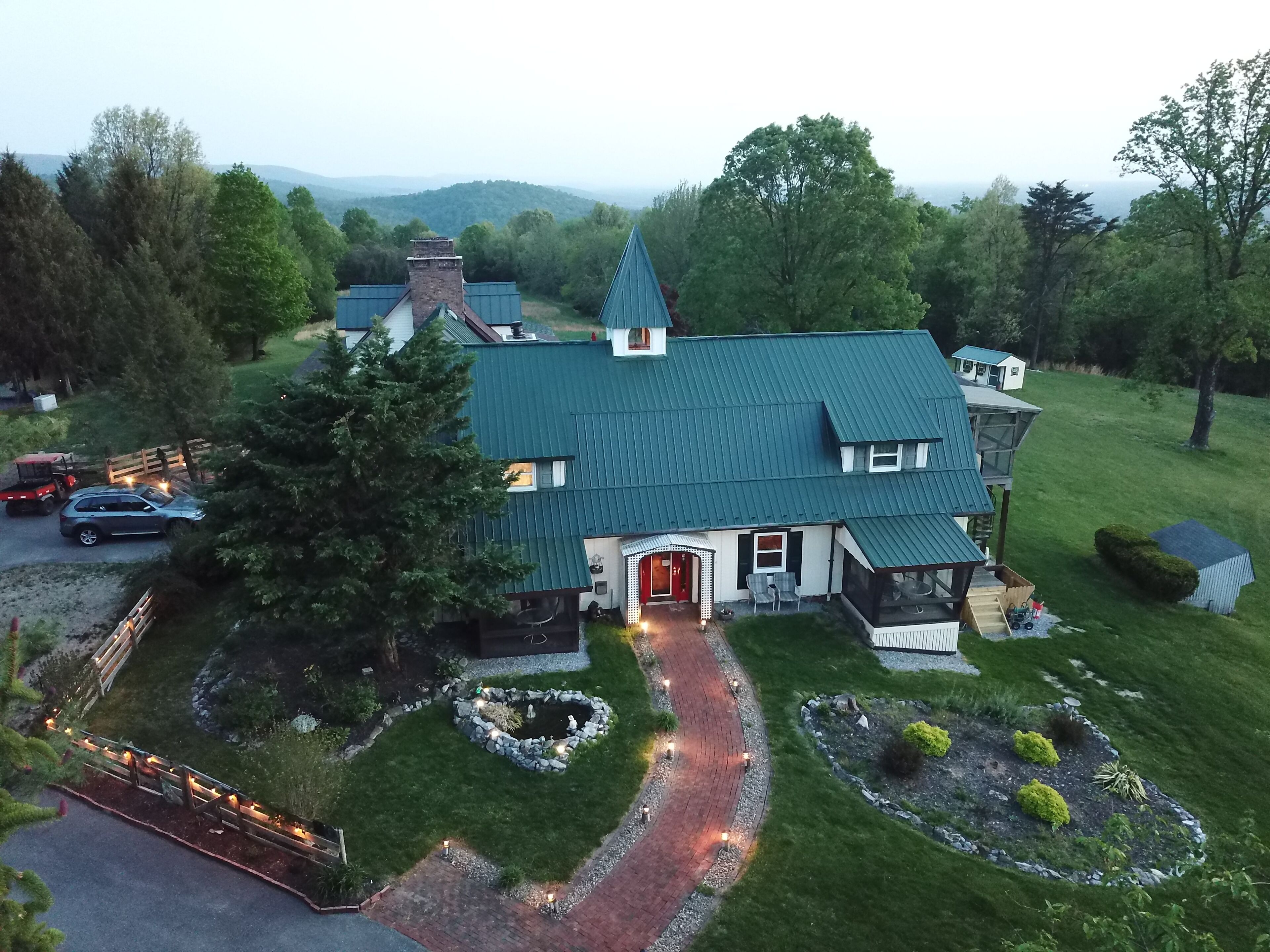 A large house with a green roof, surrounded by a well-maintained lawn and garden.