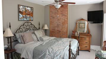 A bedroom with a bed, a dresser, a mirror, a television, and a ceiling fan.
