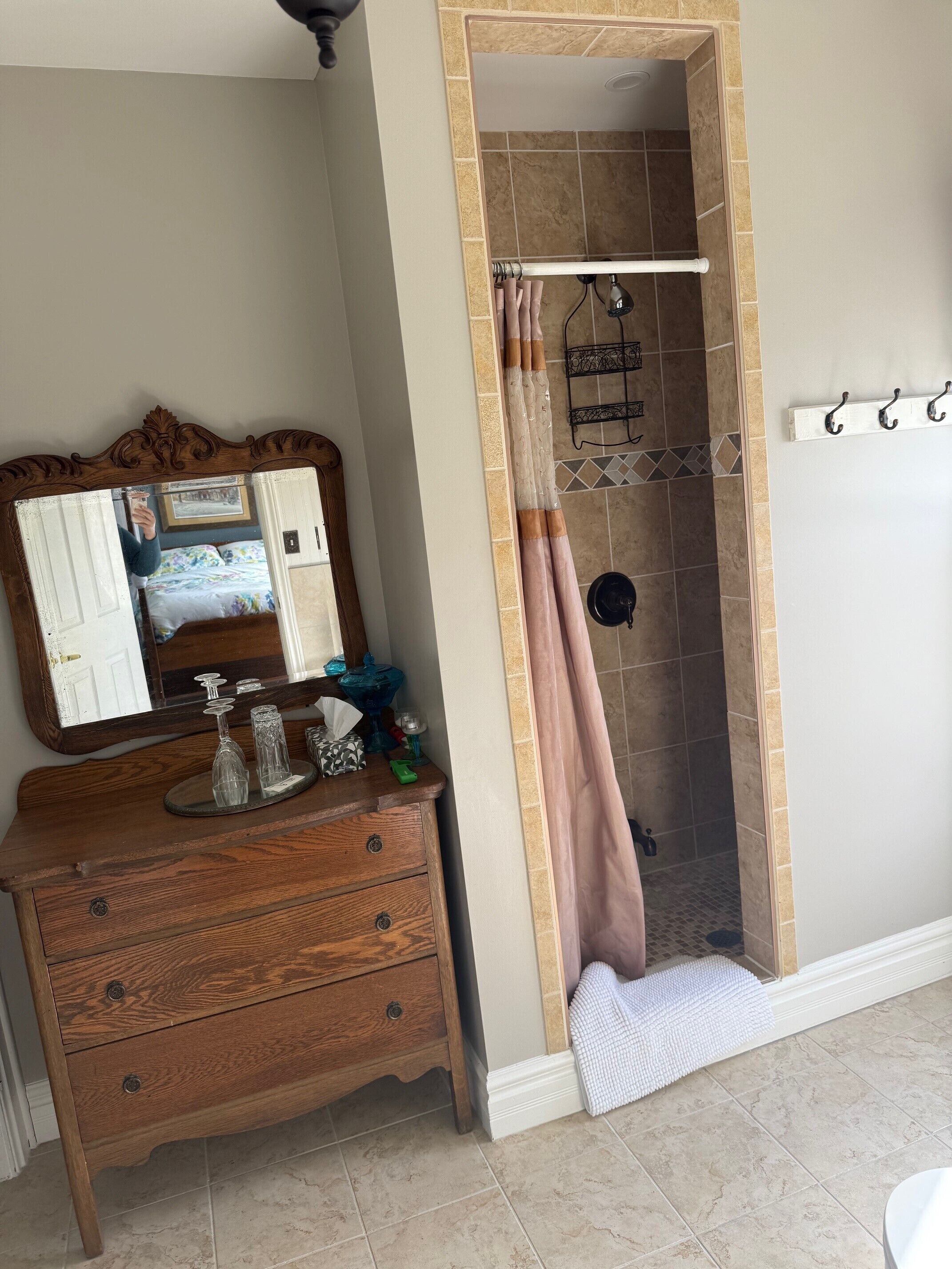 A bathroom with a wooden vanity, a mirror, a shower with a curtain, and a towel rack.