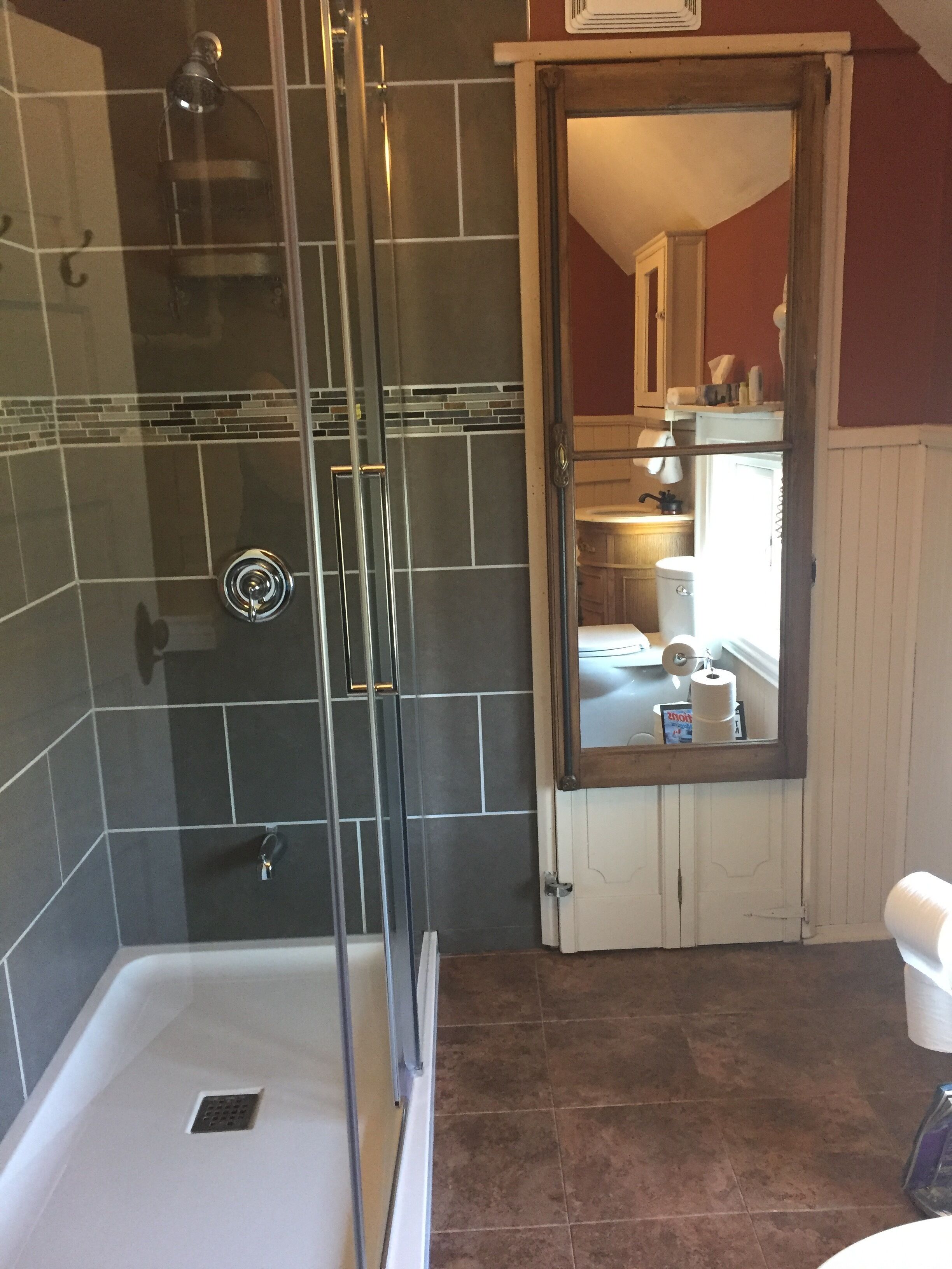 Een badkamer met een douchecabine van glas, een witte badkuip en een zichtbaar toiletrol.
