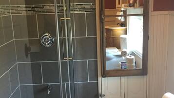 Een badkamer met een douchecabine van glas, een witte badkuip en een zichtbaar toiletrol.