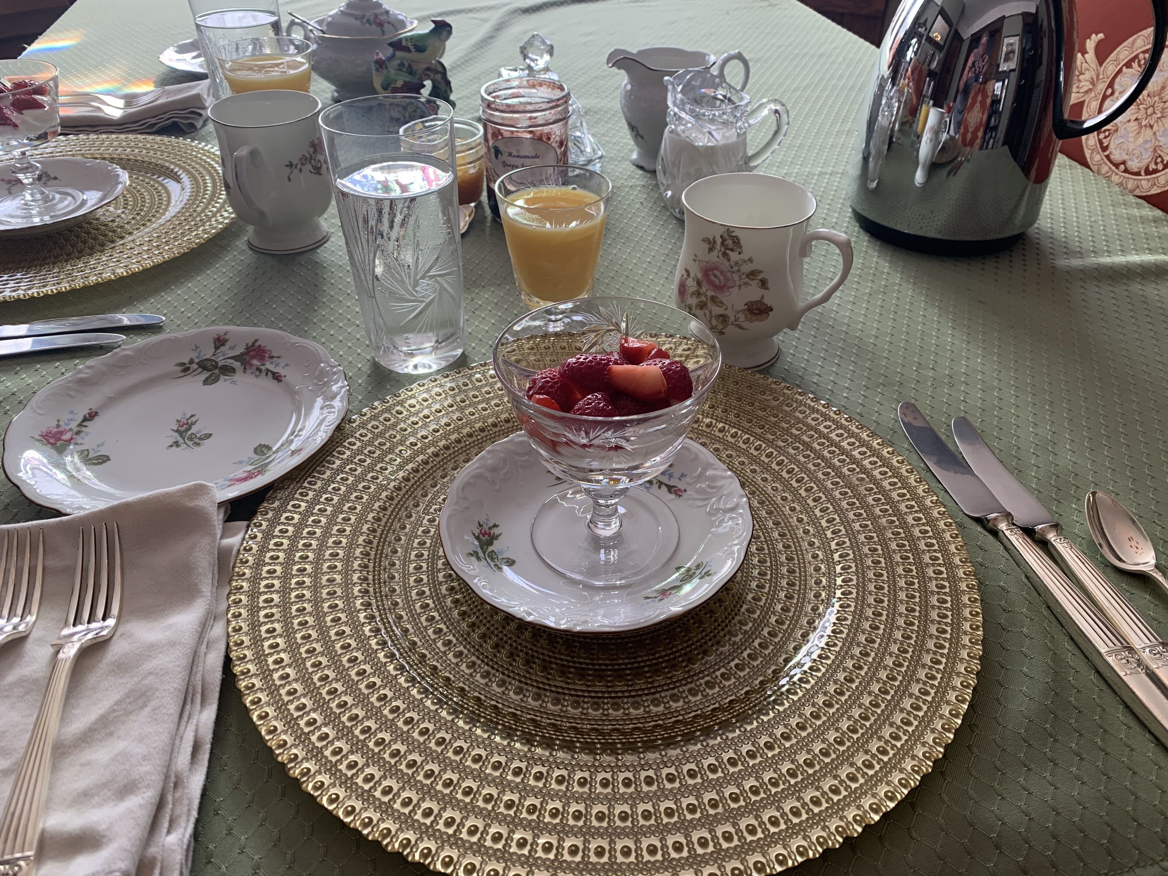 A table set with fine china, glassware, and silverware, indicating a formal dining arrangement.