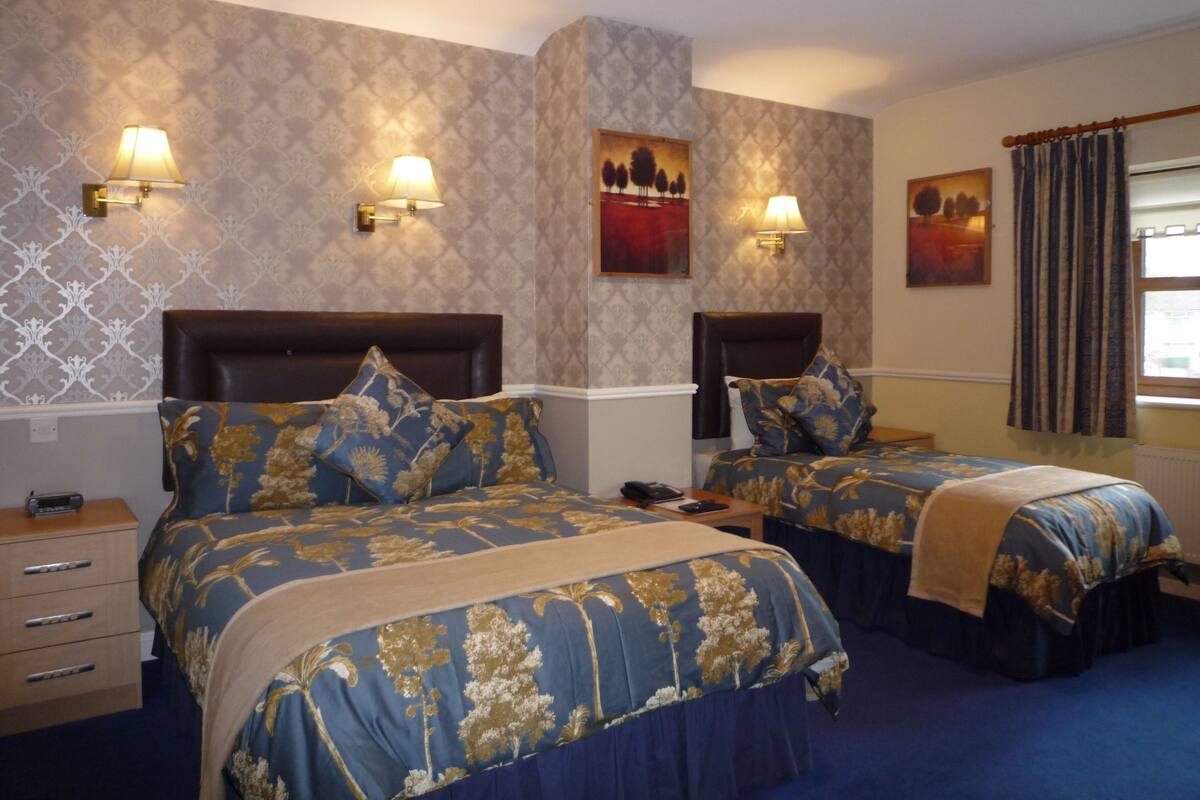 Une chambre d’hôtel avec deux lits, chacun doté d’une tête de lit, d’une table de chevet et d’une lampe.