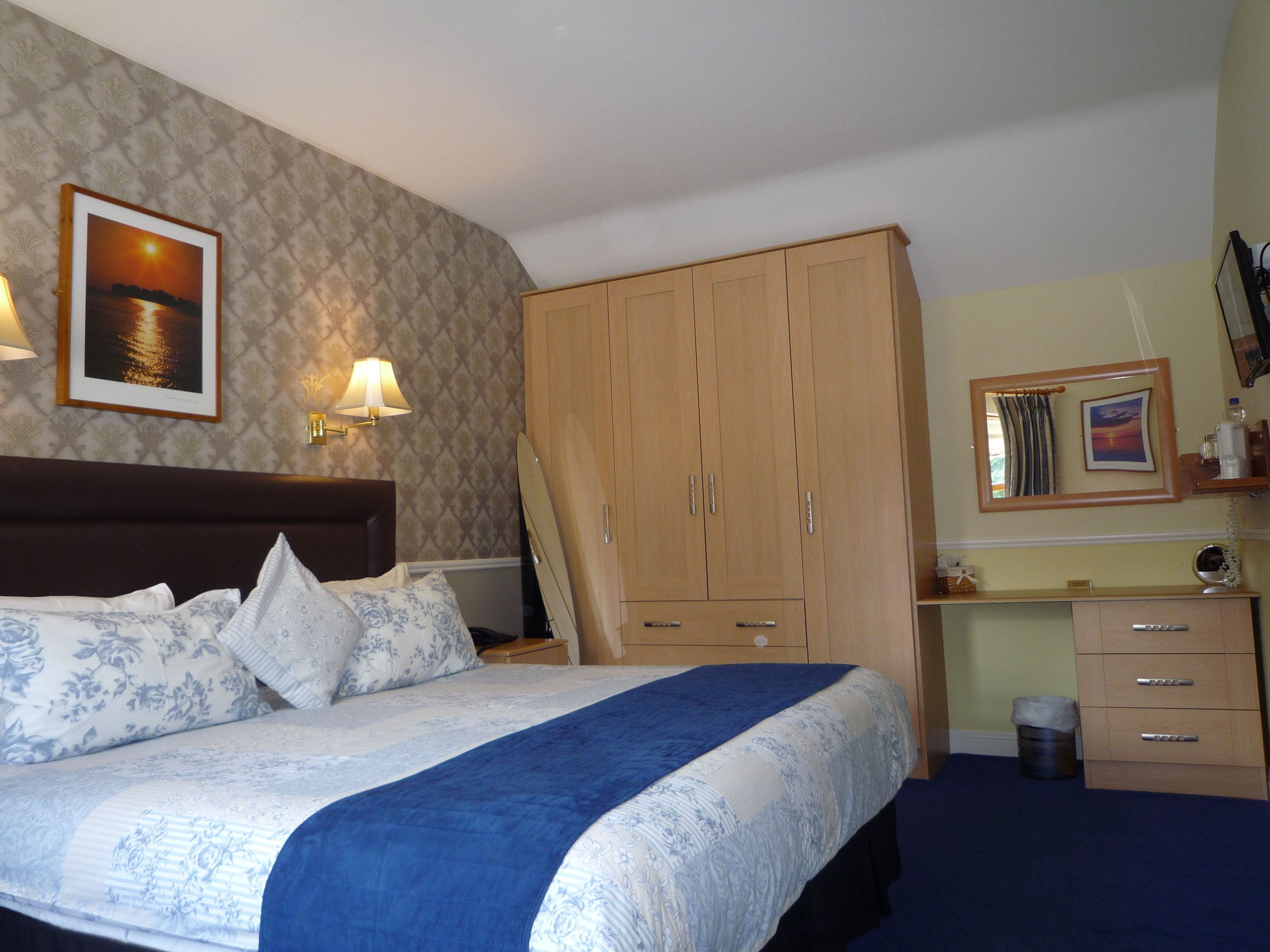 Una habitación de hotel con cama, armario, escritorio y espejo.