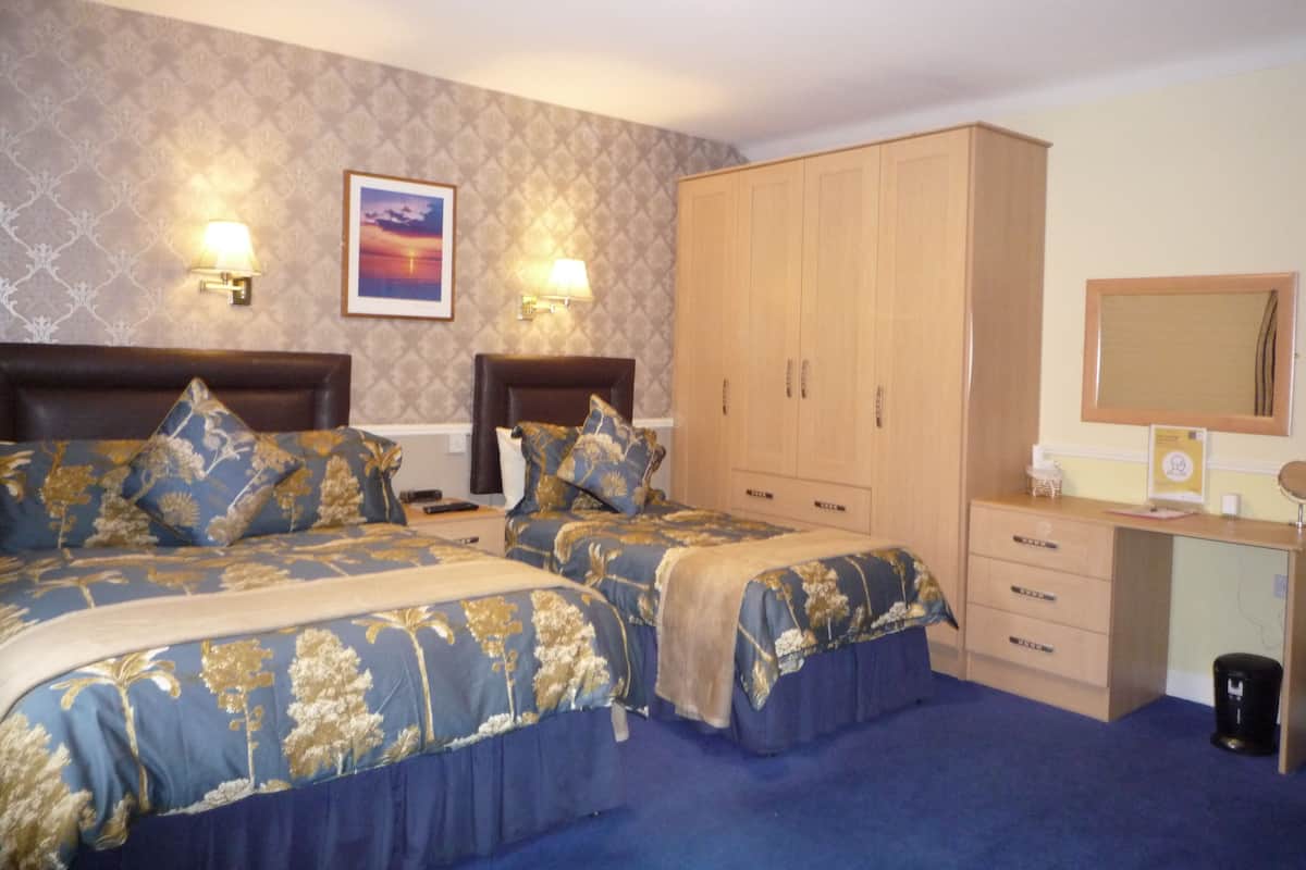 Une chambre d’hôtel avec deux lits, un bureau, un miroir et une armoire.