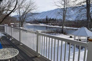 A deck with a view of a river and mountains.