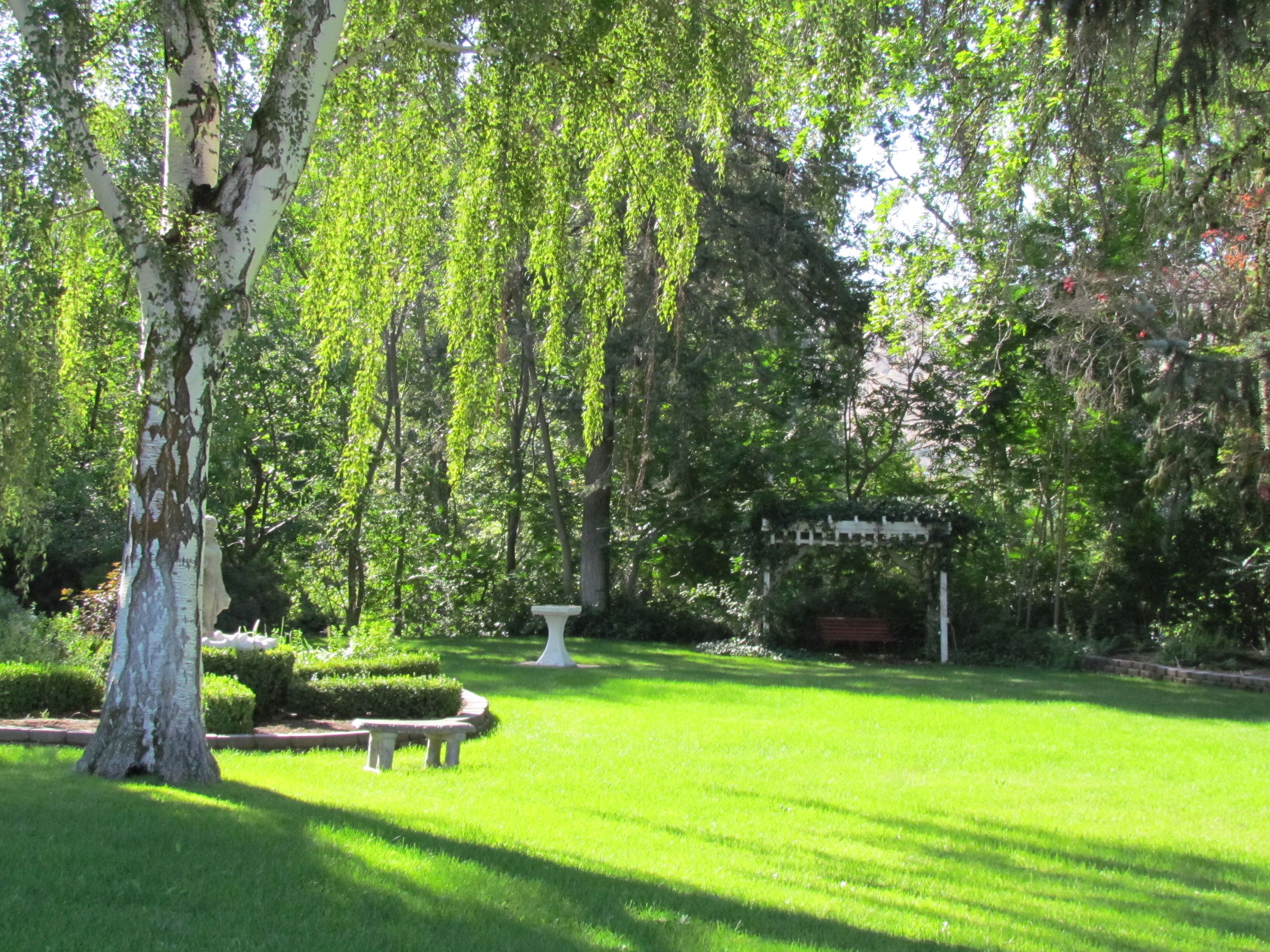 A well-maintained garden with a gazebo, neatly trimmed hedges, and a bench.